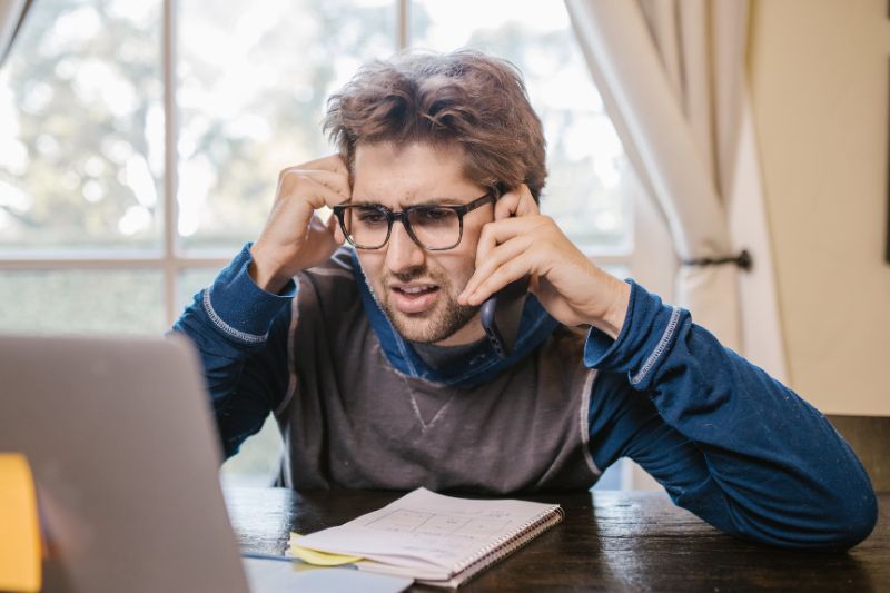 Confused man looking at his laptop, wondering why his tax refund is delayed.