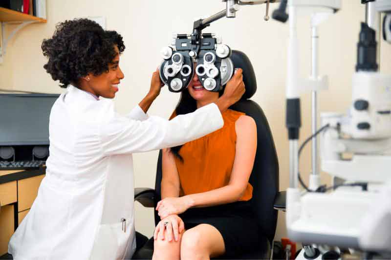 Woman getting her eyes checked by an eye doctor, symbolizing medical expenses that may be tax deductible.