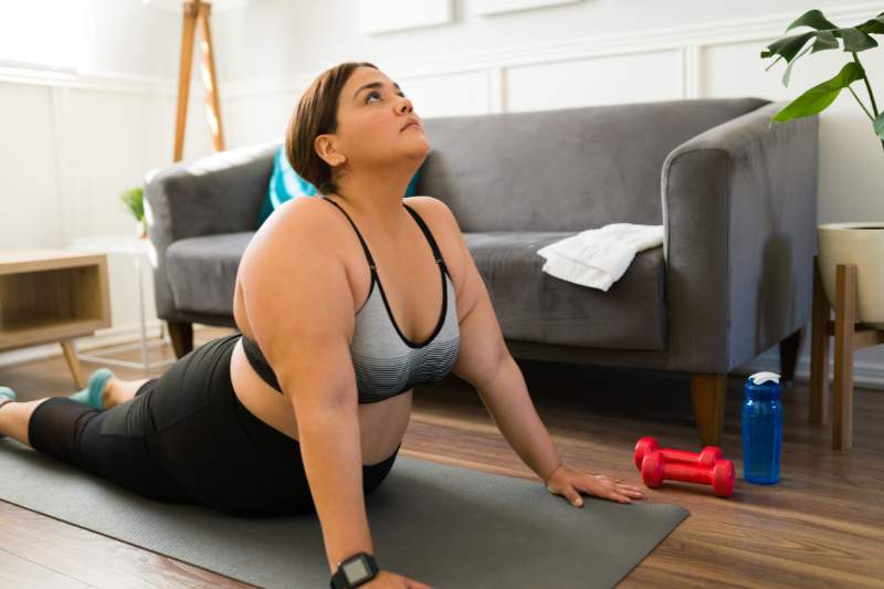 A woman practicing yoga at home, investing in her health and well-being as part of a personal growth and self-care routine.