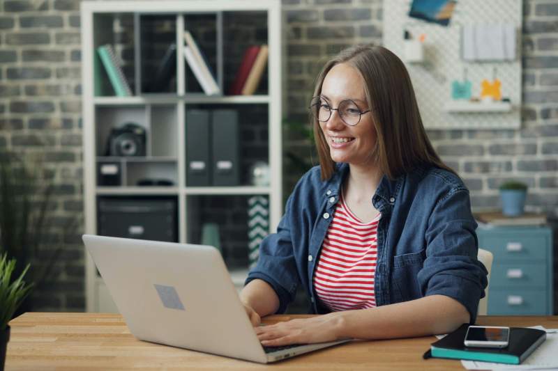 Woman smiling at laptop while reviewing year-end IRA reminders and retirement contributions.