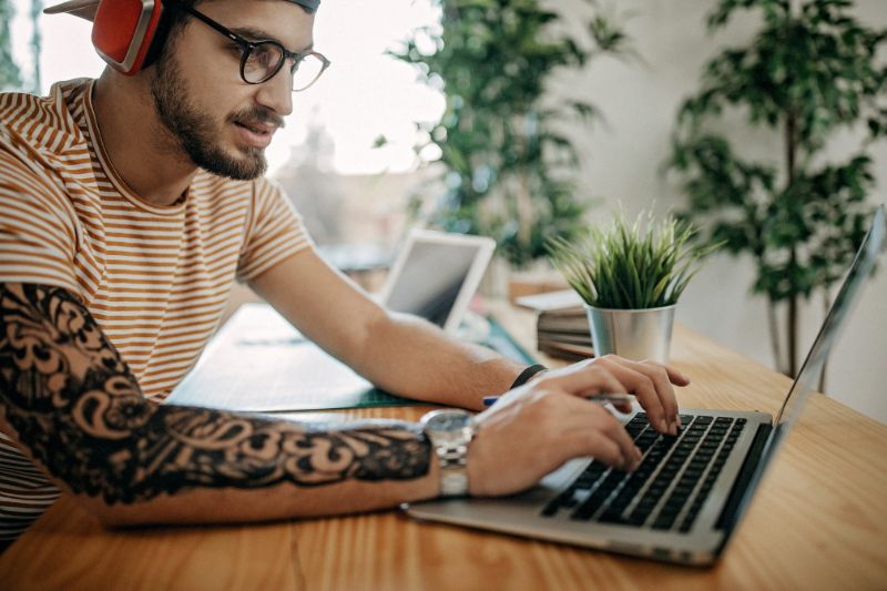 A young man using his laptop to research and learn about different types of taxes, including income, property, and sales taxes.