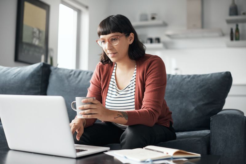 Woman reviewing 2025 tax law changes on her laptop at home with a cup of coffee, staying updated on new tax rules and refund impacts.