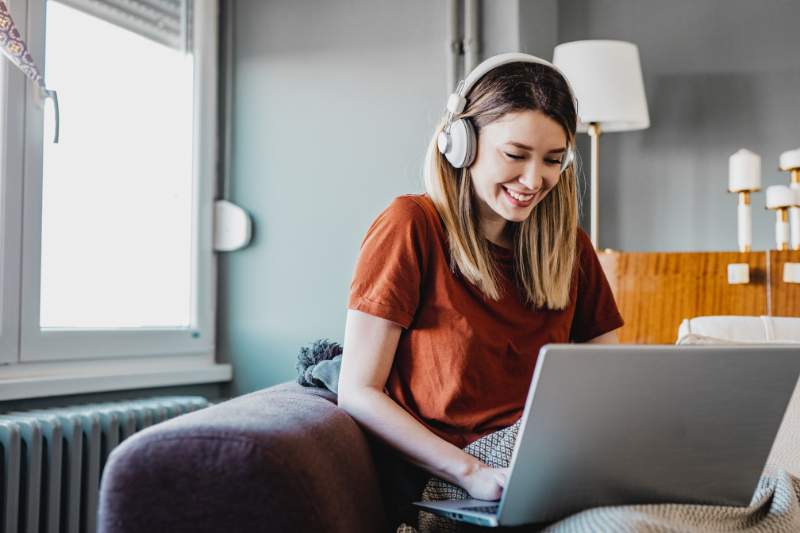 Woman working from home on laptop with headphones, representing tax write offs for working from home.