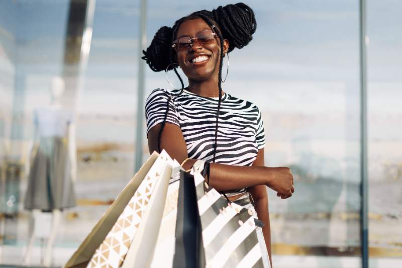 Happy young woman holding shopping bags during tax-free weekend shopping event.