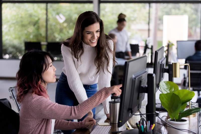 Coworker helping with a computer issue, showing how to ask for help effectively.